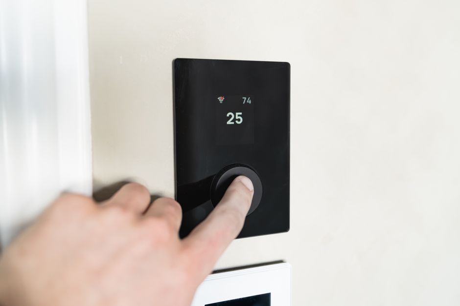 Homeowner adjusting a smart thermostat for better heating and cooling